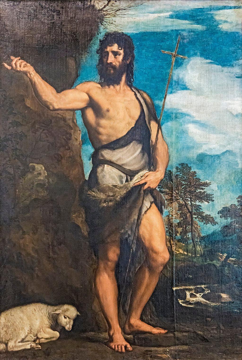 Saint John the Baptist by Titian | Gallerie dell’Accademia Venice. Painting of a bearded man with a cross, possibly a religious figure, in a natural setting.