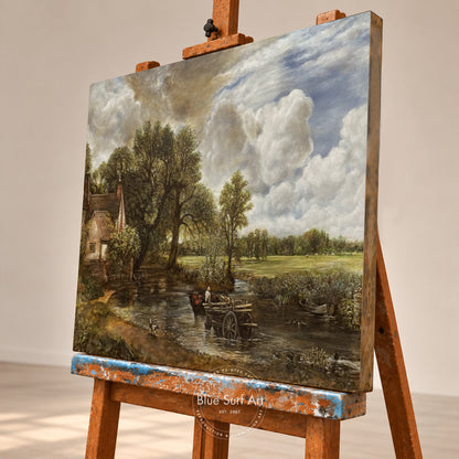 A canvas painting of a Dutch-style landscape with a cloudy sky, trees, a small cottage, and a figure by a stream, displayed on a wooden artist easel in a studio setting.