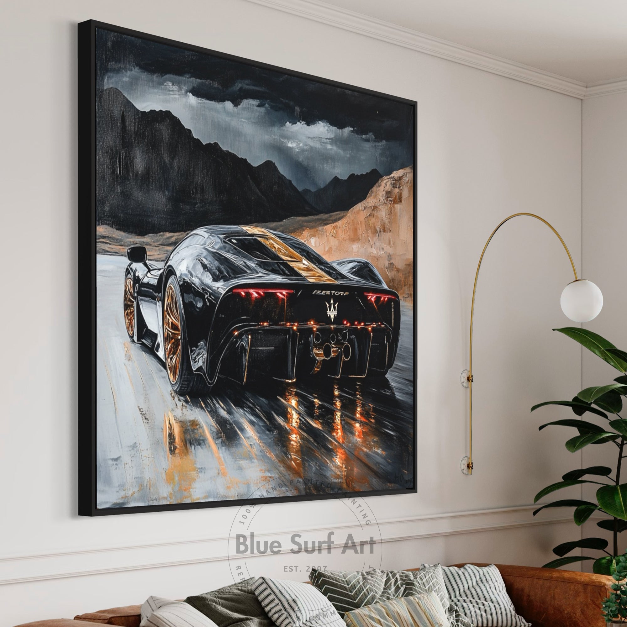 Framed artwork of a black sports car on a mountain road, displayed in a living room.